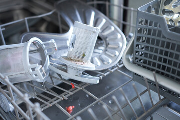 A broken dishwasher with the door open. Close-up. Selective focus.