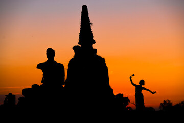 Silhouette women take Thai dancing  to respect buddha and ancient pagoda in temple at sunset time.