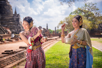Beautiful Asian woman wearing Thai dress traditional pose happiness to playing splash water during...