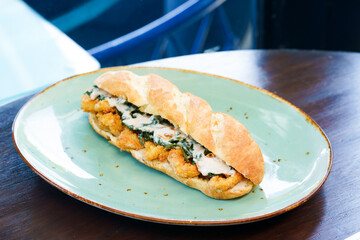 Top-down view of a sub sandwich with egg, meat, and vegan on a green plate