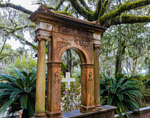 Cross Framed By Arch Monument Under Moss Covered Oak Trees at Bonaventure Cemetery Near Savannah ,...