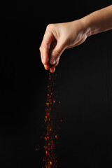 Hand holding cayenne pepper on black background