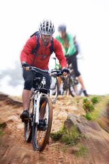 Man, bicycle and cycling on dirt road for fitness, extreme sports or cardio exercise in nature. Male person, athlete or cyclist riding bike on rocky path, trail or outdoor slope with motion blur