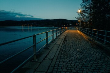 figure of a man stands on a bridge under the light of a lantern