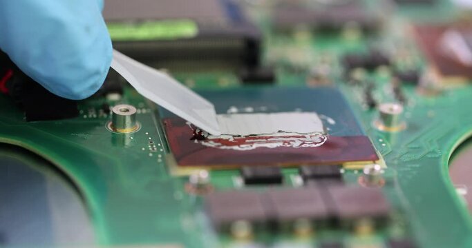 Repairman applying thermal paste on computer motherboard in workshop closeup 4k movie slow motion. Electronics repair of computers and laptops concept