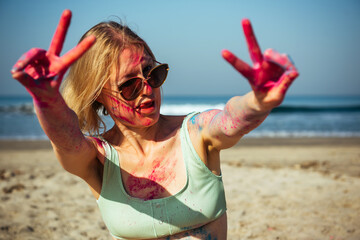 Beautiful sensual blonde woman covered in rainbow colored powder celebrating Holi Festival near the...