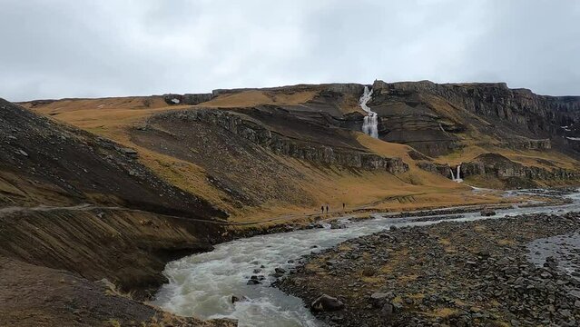 Hengifoss waterfall in Iceland with Hengifossa river gorge and red basaltic layers of clay, panoramic shot