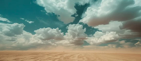 Foto op Plexiglas The sky is filled with swirling clouds above a vast dirt field. The clouds seem to dance gracefully over the open expanse of the desert, creating a captivating visual display. © 2rogan