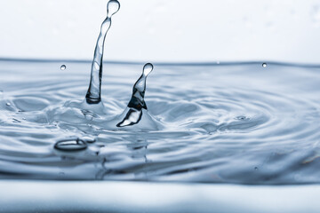 A drop bouncing off clean, transparent water, creating a splash effect and a shape imitating people