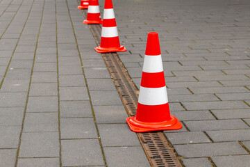 red and white road cones on a footpath