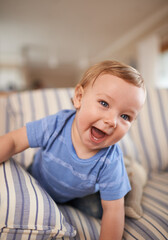 Playing, laughing or portrait of baby in sofa or home for fun, growth or learning alone in living room. Happy, boy or face of a playful male kid on couch for child development or crawling in a house