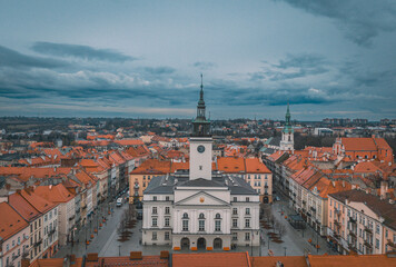 Fototapeta na wymiar illuminated night view of the town hall in Kalisz, Poland from a drone, dramatic blue sky before rain, view of old tenement houses and architecture