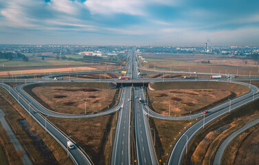 road loops, motorway, expressway with exits in front of the city, modern road infrastructure, construction and architecture in the background blue sky