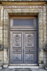 Visualize a scene featuring an ancient ornate doorway adorned with intricate patterns and designs, crafted from aged, weathered wood or stone, and framed by elaborate stained glass windows. - obrazy, fototapety, plakaty