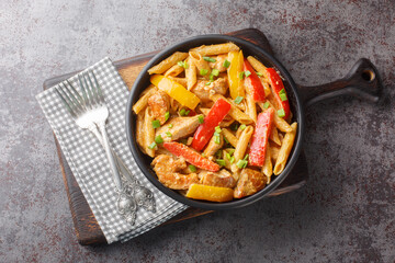 Jamaican Style Rasta Pasta Penne with Grilled Chicken and Bell Peppers closeup on the bowl on the wooden board. Horizontal top view from above