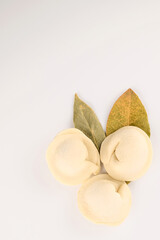 homemade raw dumplings and bay leaf, close-up top view, on a white background