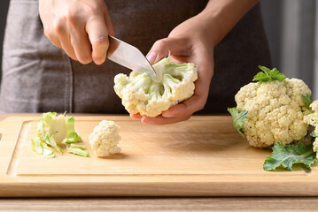 Hand holding knife and cutting organic cauliflower, Homemade cooking