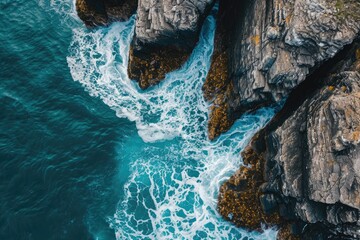 An aerial perspective captures the vast expanse of the ocean and the rugged beauty of the rocky coastline, Striking overhead view of a sea creating foamy patterns around rocky outcrops, AI Generated