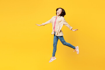Fototapeta na wymiar Full body side view young woman of Asian ethnicity she wear pink t-shirt beige shirt pastel casual clothes run jump high pov fly isolated on plain yellow background studio portrait Lifestyle portrait