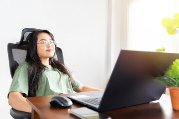 Young woman crossed hands behind head, enjoying break time at home. Peaceful carefree business woman resting at table with computer.