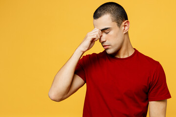 Young exhausted weary frustrated sick ill sad middle eastern man he wear red t-shirt casual clothes keep eyes closed rub put hand on nose isolated on plain yellow orange background. Lifestyle concept.