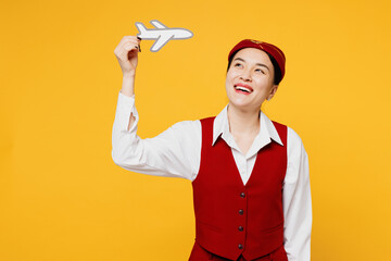 Young smiling fun stewardess flight attendant woman of Asian ethnicity she wear red vest shirt hat...