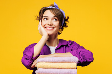 Young minded smiling happy woman she wear purple shirt do housework tidy up put hand on pile of...