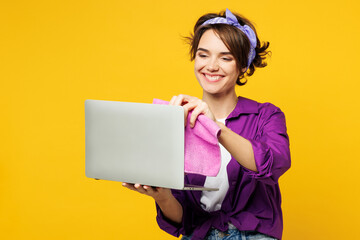 Young IT woman wears purple shirt hold basin with detergent bottles do housework tidy up use work...