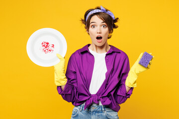 Young surprised woman wear purple shirt rubber gloves casual clothes do housework tidy up wash...
