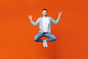 Fototapeta na wymiar Full body young man wear blue shirt white t-shirt casual clothes jump high hold spread hands in yoga om aum gesture meditate try to calm down isolated on plain red orange background Lifestyle concept