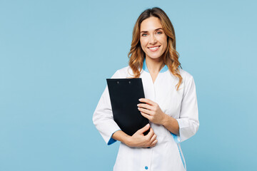 Female confident happy doctor woman she wears white gown suit work in hospital clinic office holding clipboard with medical documents isolated on plain blue background. Health care medicine concept.