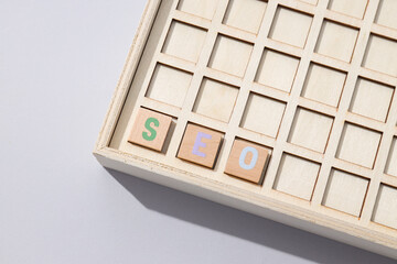 Wooden box with cells and wooden cubes with letters on light background, top view