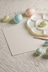 Fototapeta na wymiar Easter, spring, copy space, Easter decorative eggs in pastel colors and narcissus on the table, white background, watercolor paints and palette, 