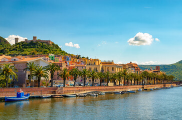Picturesque view of Bosa town along Temo River in Sardinia, Italy, with colorful buildings and palm trees