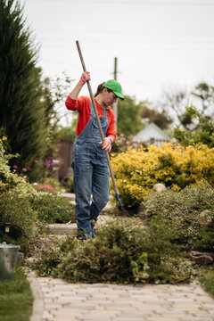 A young woman pulls weeds in her huge garden in the spring, clearing the garden after winter