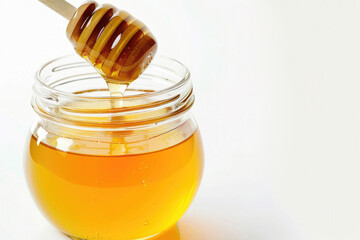 A jar of honey with a dipper, against a white backdrop