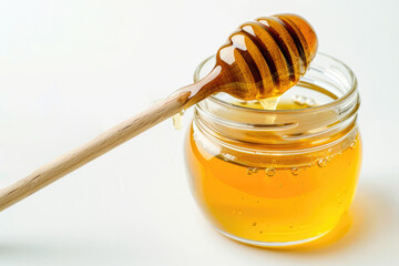 A jar of honey with a dipper, against a white backdrop