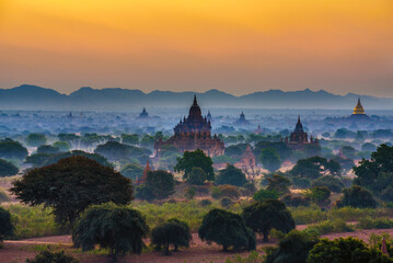 Sunrise over the ancient temples of Bagan with distant mountains shrouding the horizon in Myanmar....
