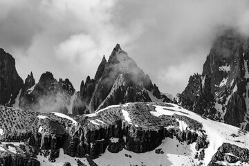 a black and white photo of mountains in the snow with some clouds