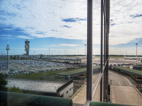 Milano, Italy - 8 august 2023: Car Parking and Airport Control Tower reflected on office windows, Milan Malpensa Airport -Italy