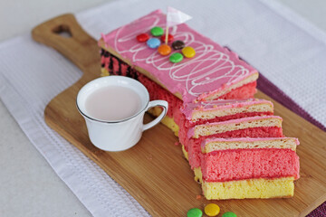 a piece of sponge cake with a cup of strawberry milk on the table