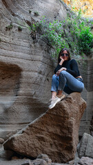 Mujer en sitio con paredes de roca y picón en la isla de Gran canaria con ropa normal de mujer gafas de sol posando natural