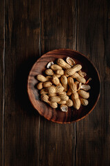 Peanuts in a wooden dish, on wooden table. Top view.