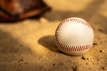 Fototapeta na wymiar Baseball ball and glove on the sand. Close up