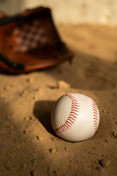 Baseball ball and glove on the sand. Close up