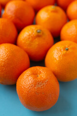 Fresh orange fruits on light blue background, vibrant vertical photo of citrus food in line