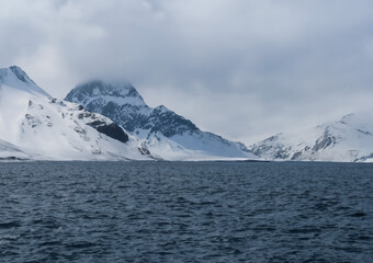 Antarctic landscape with icebergs and mountains in the background.