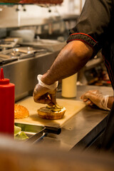 man assembling burger with pickles
