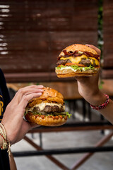 two friends holding a cheeseburger in each hand