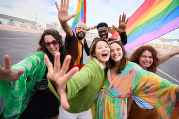 A crowd of happy people in colorful wear smile for a selfie with a rainbow flag, capturing their fun and leisurely travel recreation in the pride day. LGBT diverse people united for the community